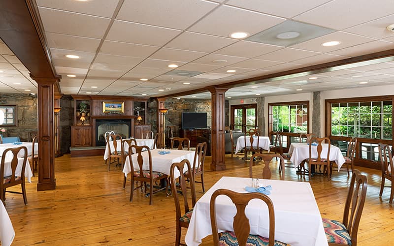 A spacious restaurant interior featuring wooden floors and tables set for dining.