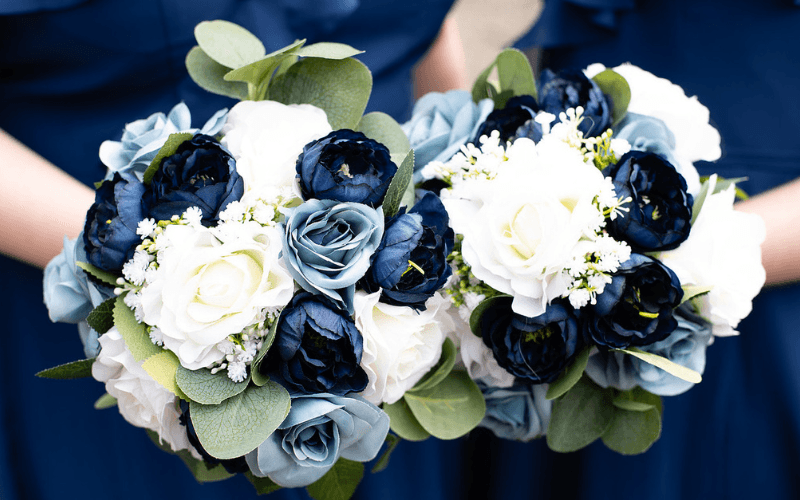 Two bridal bouquets featuring white and navy blue flowers with greenery.