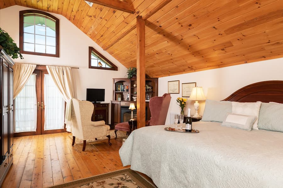 A cozy, warmly lit bedroom features a large bed, a sitting area, and wooden accents.
