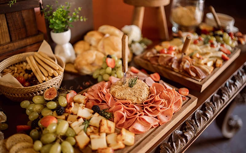 A beautifully arranged platter of meats, cheeses, fruits, and bread on a rustic wooden table.