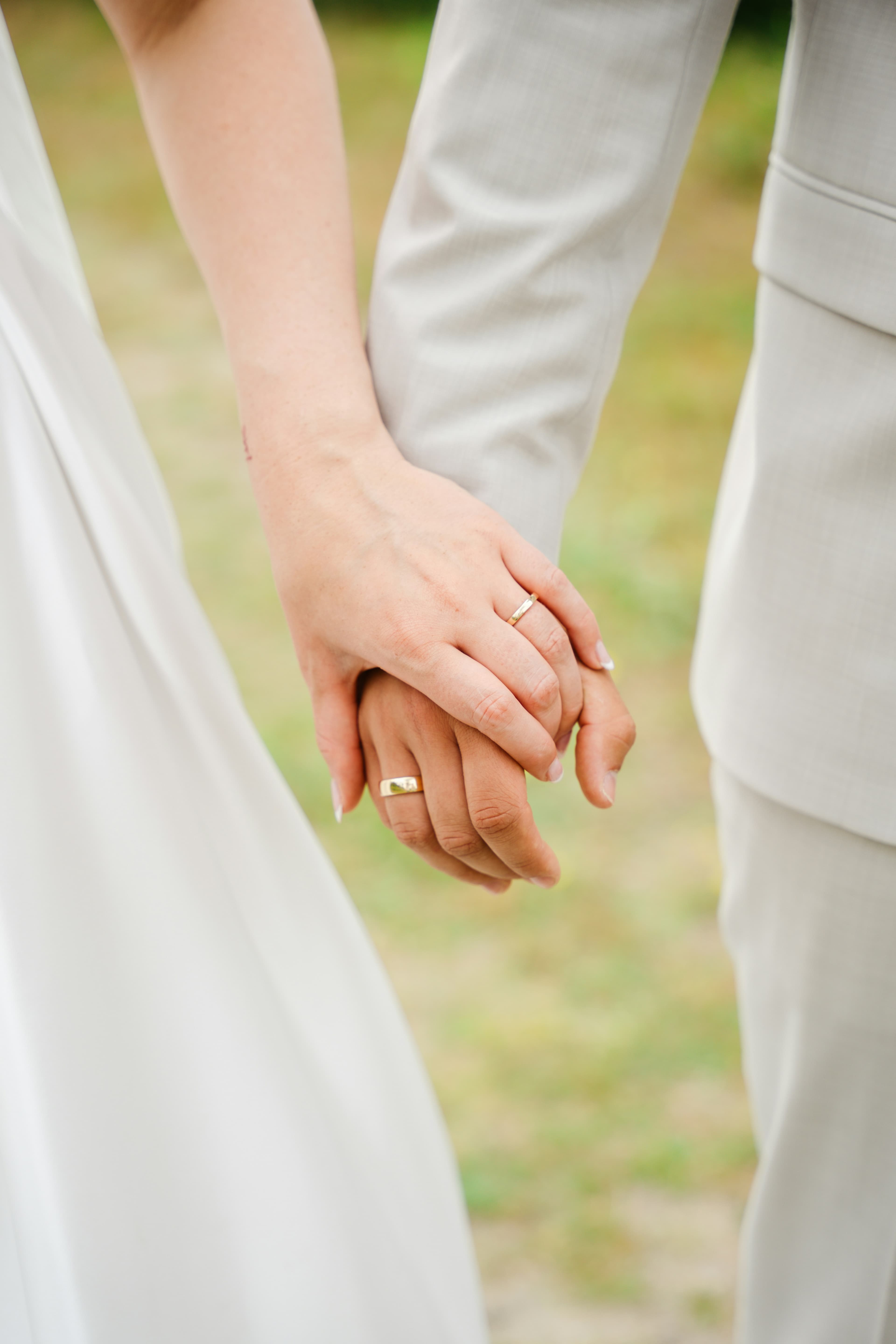 A close-up of two hands holding each other, adorned with wedding rings.