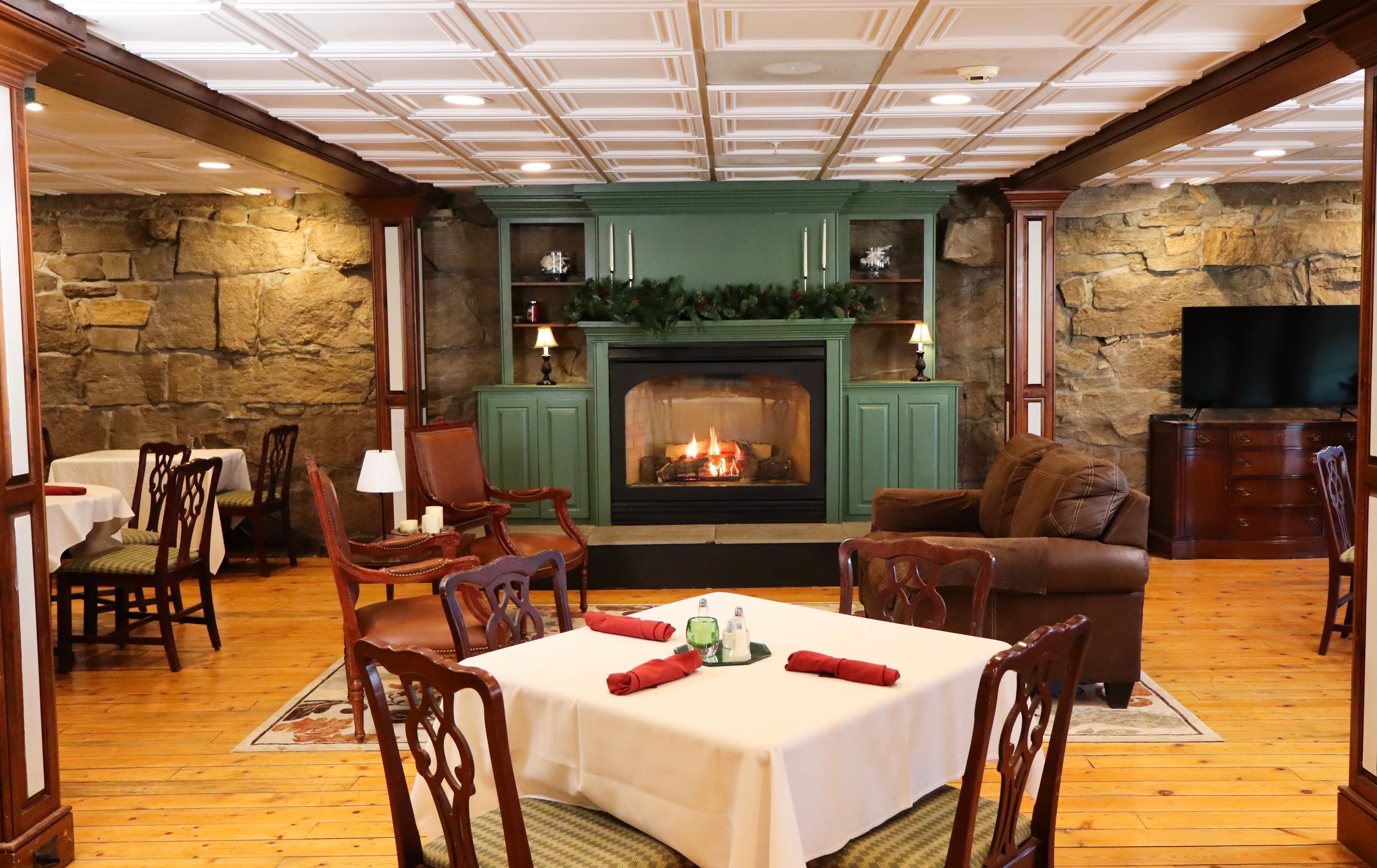 Cozy dining area featuring a fireplace, wooden floors, and rustic stone walls.