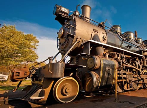 A close-up of a vintage steam locomotive under a clear blue sky.