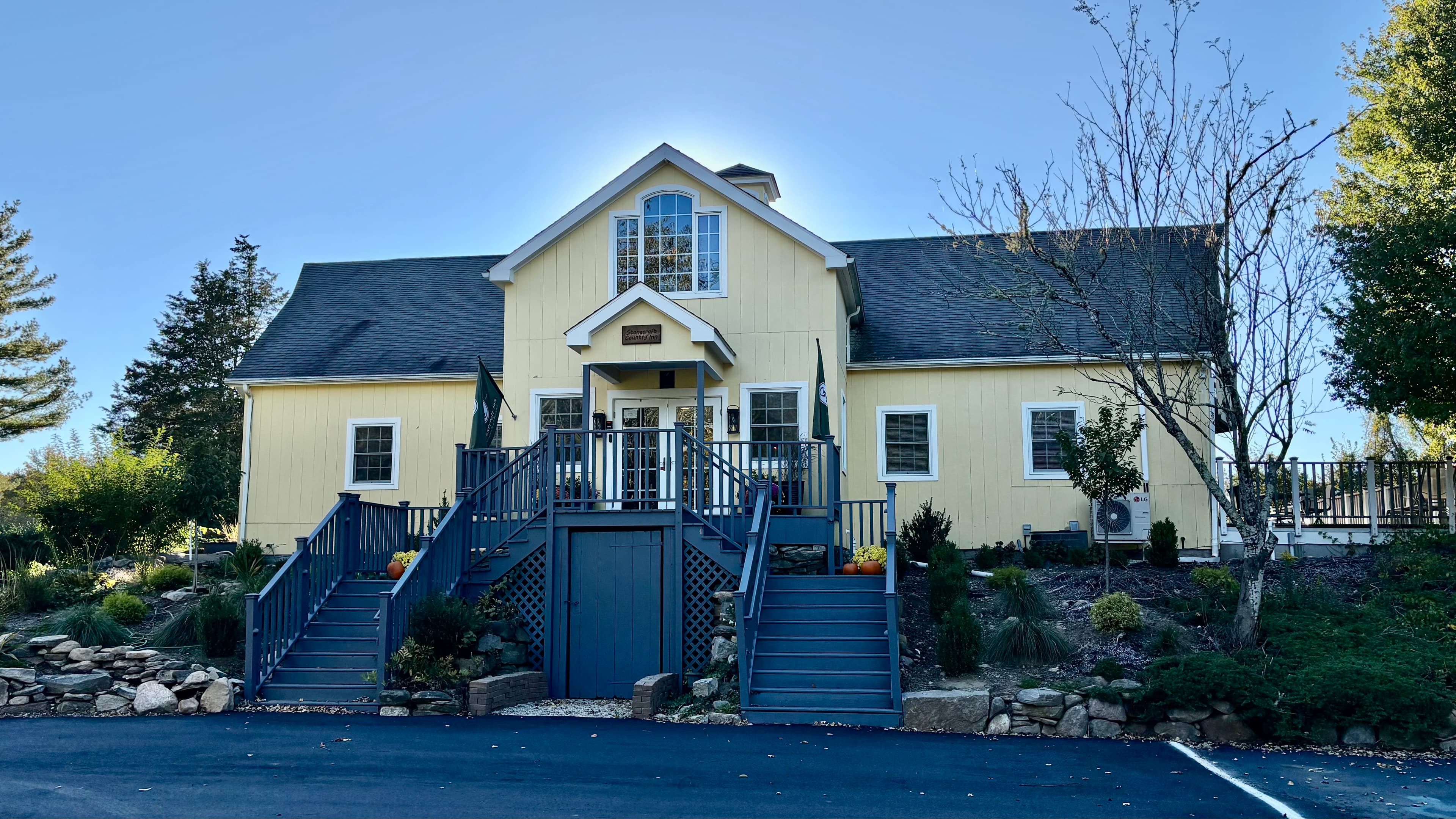 A large yellow house with steps leading up to a front porch, surrounded by greenery.