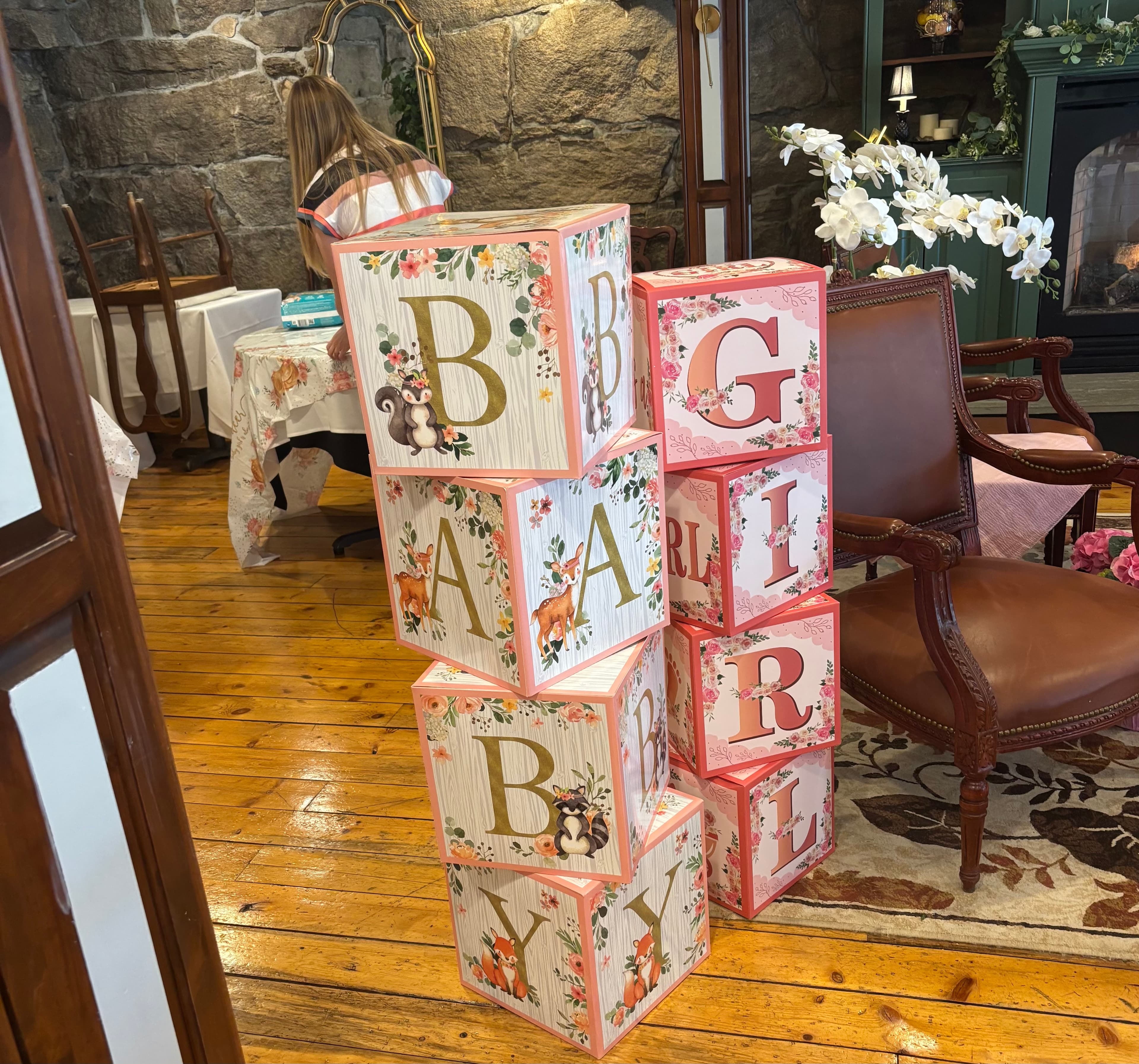 Stacked decorative blocks spelling "BABY GIRL" in a cozy room setting.